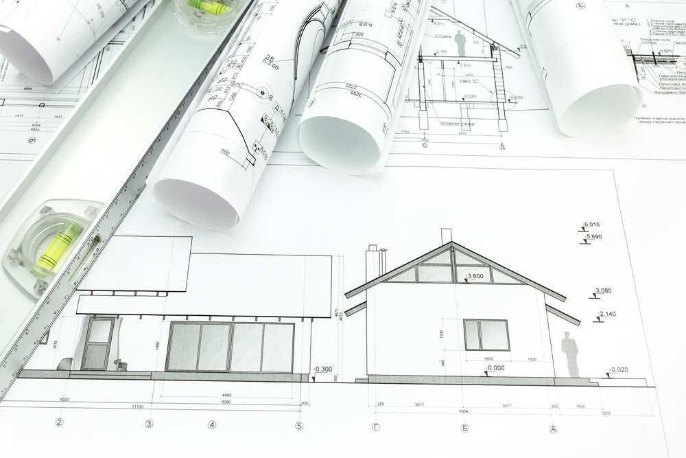 Architectural house plans, rolled blueprints and a spirit level on a desk