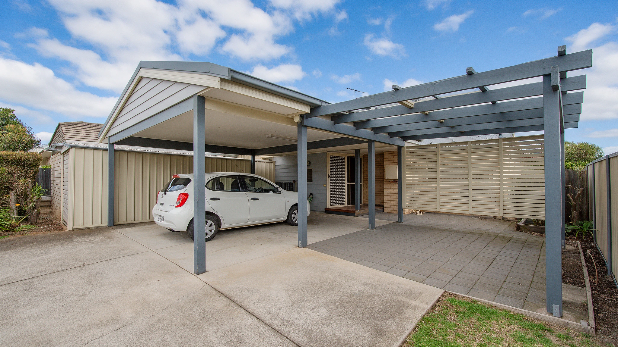 Carport and pergola alongside a suburban home